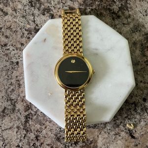 Movado watch with black face and gold chain band